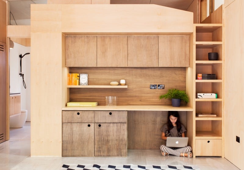 The bright and airy wood-paneled interior was designed to be as compact as possible. A combined lounge, dining area, and kitchen sit on one side, while a wall of cabinets sits opposite the bedroom with an adjoining bathroom.