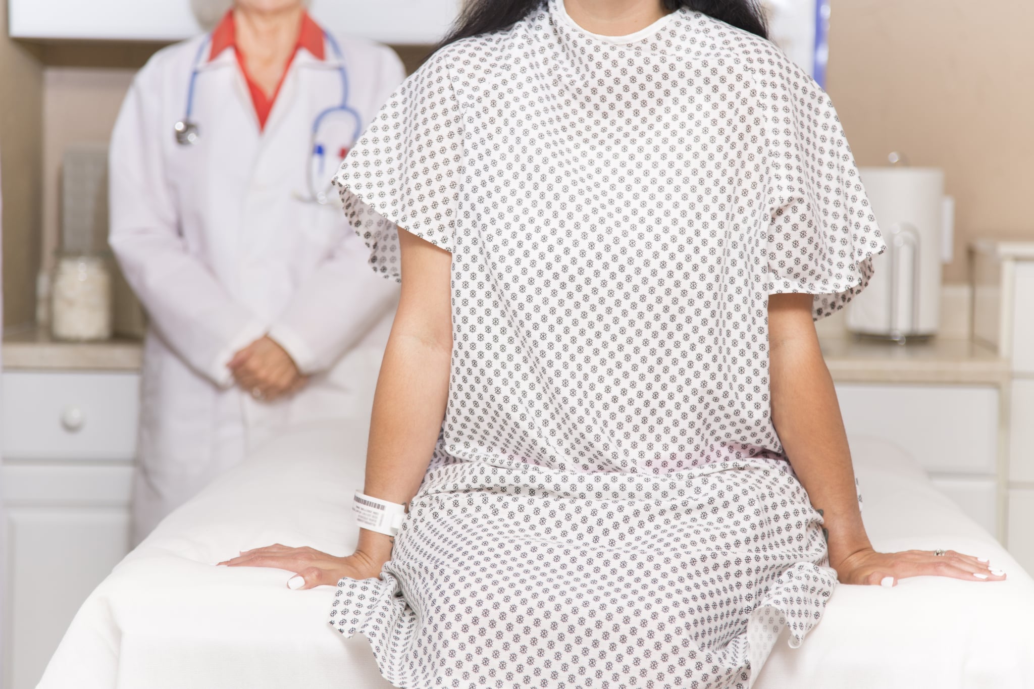 Mid-adult, latin descent woman prepares for her annual breast exam, mammogram from her gynocologist doctor at hospital or clinic.  Or woman wearing hospital gown prepares for medical procedure.  Senior adult, female doctor.  Women's health, issues.  Breast cancer awareness.
