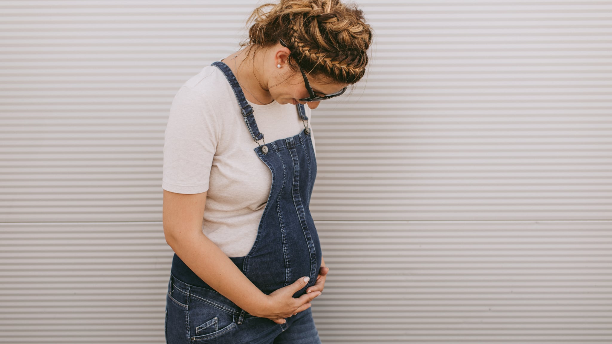 Portrait of an urban pregnant woman stroking her growing belly // wide photo dimensions