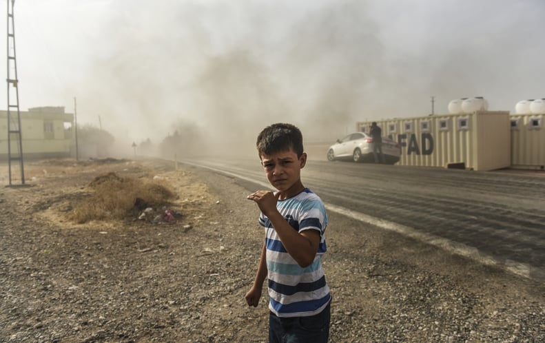 A boy watches as Turkish forces drive toward the Syrian border.