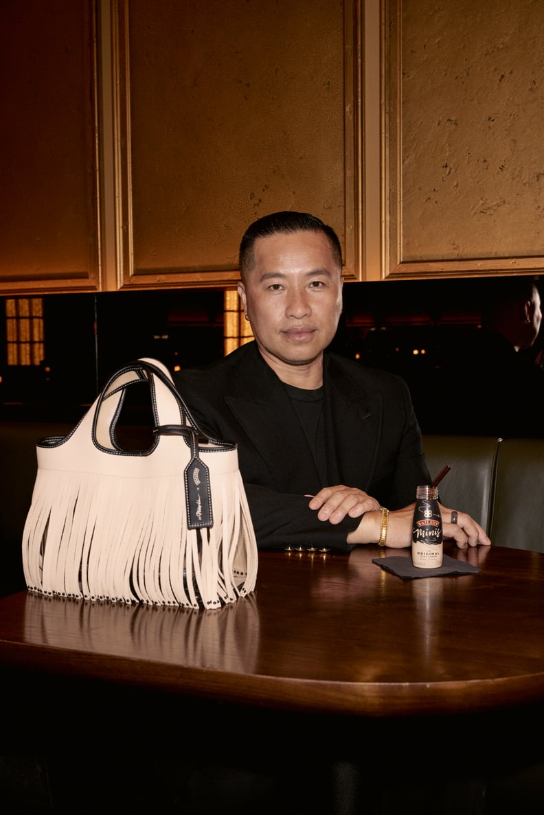 A photo of designer Phillip Lim sitting at a bar table with the 3.1 Phillip Lim x Baileys tote bag in the foreground and a mini Baileys drink next to him.