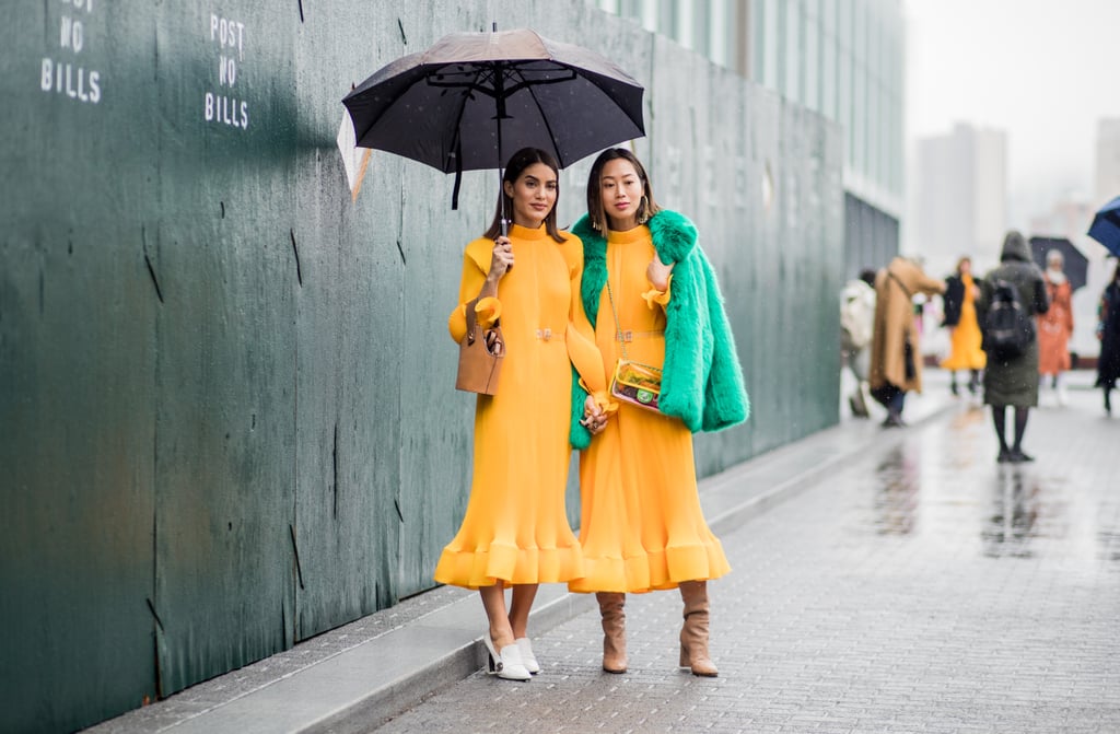 Camila Coelho and Aimee Song both wearing the same yellow Tibi dress outside the brand's show.
