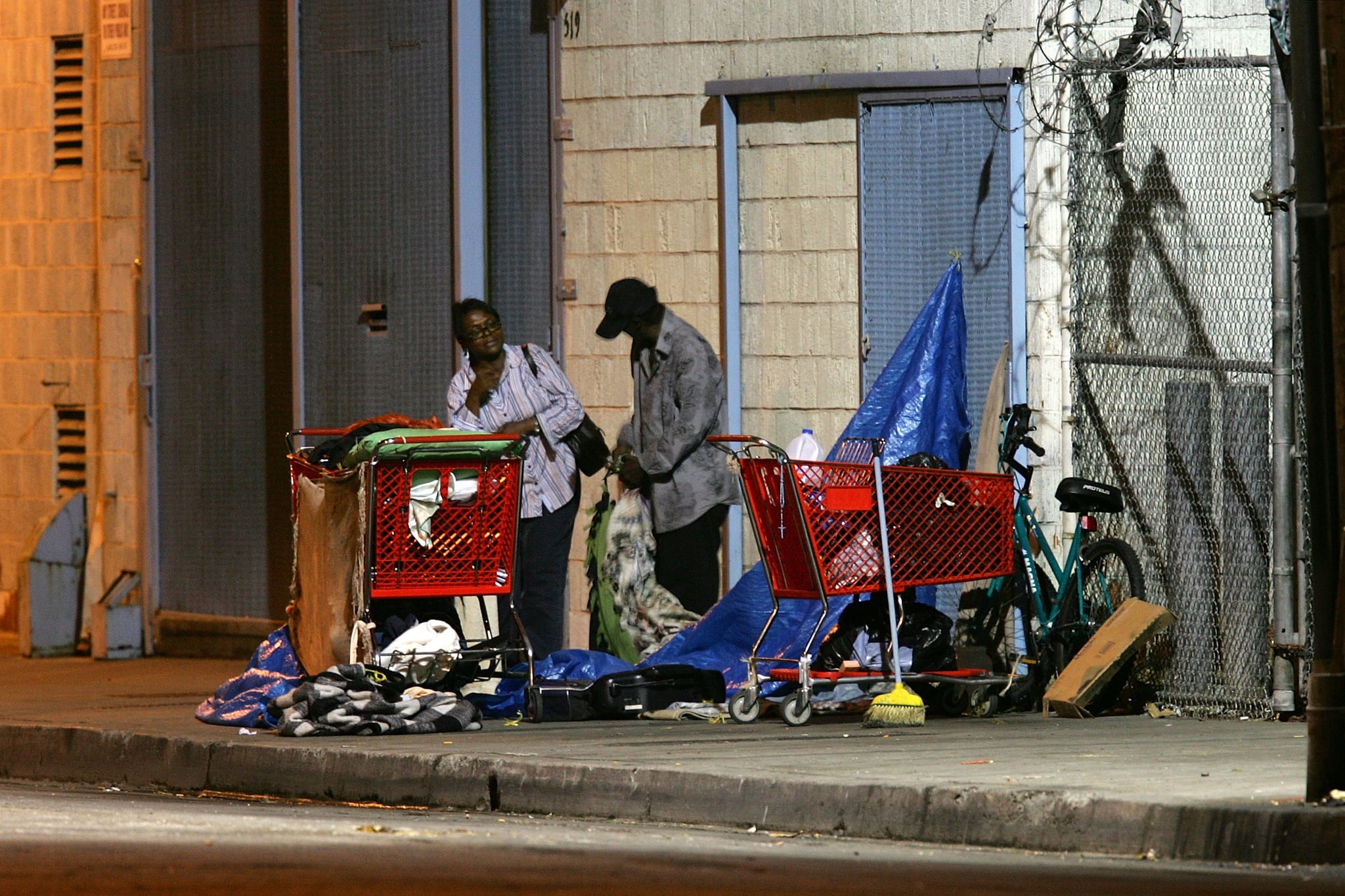 LOS ANGELES, CA - OCTOBER 12:  A homeless couple gets up before dawn to dismantle their encampment before businesses open October 12, 2007 in the downtown Skid Row area of Los Angeles, California. Los Angeles city officials recently settled a 2003 lawsuit brought by advocates for homeless skid row residents who complained of being arrested for sleeping on sidewalks, despite having nowhere else to go. Under the new deal, people can sleep on Los Angeles sidewalks between 9 p.m. to 6 a.m. as long as they do not block doorways or driveways, or completely block the sidewalk. Los Angeles is often referred to as the homeless capital of the nation because of its estimated 40,144 people living on city streets and 73,000 homeless spread across the county, according to recent figures attributed to the Los Angeles Homeless Services Authority, The 73,000 homeless include 10,000 minors, 24,505 people suffering from a mental illness, 8,453 military veterans, and nearly 7,200 victims of domestic abuse.  (Photo by David McNew/Getty Images)