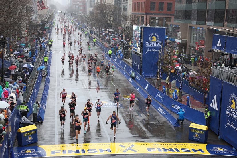 BOSTON, MASSACHUSETTS - APRIL 17: Runners celebrate in the rain as they cross the finish line during the 127th Boston Marathon on April 17, 2023 in Boston, Massachusetts. (Photo by Omar Rawlings/Getty Images)