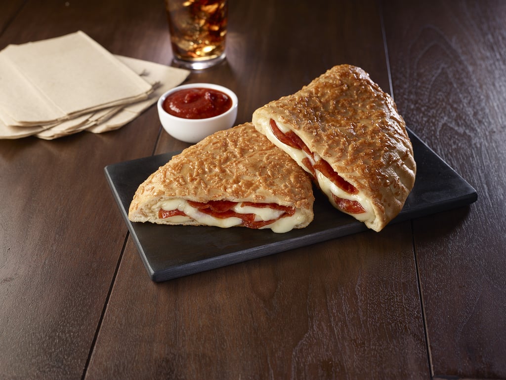 Pizza-lovers, prepare to get your parmesan on because Pizza Hut is bringing back the fan-favorite P'Zone — and the amount of cheese stuffed into these giant pizza pockets is already sending me into a mozzarella-induced nap. A Pizza Hut fan-favorite, this parmesan-crusted, calzone-inspired snack has been so popular during the last 17 years as an on-again, off-again menu item that it doesn't even need to actually be a pizza to be considered the Official Pizza of NCAA March Madness.
"We are excited to bring back the P'Zone as part of our $5 Lineup during a time when family and friends will be gathering in anticipation and excitement," said Marianne Radley, Pizza Hut's chief brand officer, in a press release. "Even if your team doesn't advance in the tournament, the comeback of the P'Zone is something we know all fans can rally around." The P'Zone is also available on its own in three savory flavors, including Pepperoni, Meaty, and Supremo. The Meaty P'Zone is made with melted cheese, pepperoni, ham, pork, beef, and Italian sausage, while the Supremo P'Zone is stuffed with green pepper, red onion, Italian sausage, and melted cheese.
So, whether you're all about the bracket picks or all about the snacking picks, keep reading for more mouth-watering photos of the P'Zone — and don't forget the marinara dipping sauce!

    Related:

            
            
                                    
                            

            Tyson&apos;s Selling Pizza-Flavored Chicken Nuggets, So Pass Me the Dipping Sauce