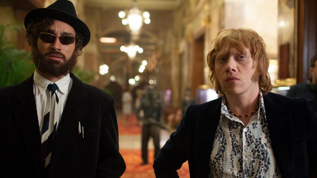 POPSUGAR: What was your favorite thing about making this movie?
Rupert Grint: It was such a fun film to work on. It was very spontaneous, and nobody really knew where it was going. I loved working with Ron Perlman and Robbie [Robert Sheehan]. Also, being on the moon and wearing an astronaut suit is kind of every kid’s dream. Overall, it was a very unique, special experience. 
PS: You play a band manager in the film. If you could have been the manager for anyone back in the '60s, who would it be? 
RG: I'll say The Velvet Underground. I'm a big fan of them.
PS: I loved how Stanley Kubrick was incorporated into the storyline. Do you have a favorite film of his?
RG: Oh, A Clockwork Orange really stayed with me. But I also love Dr. Strangelove, and The Shining is one of my favorites.