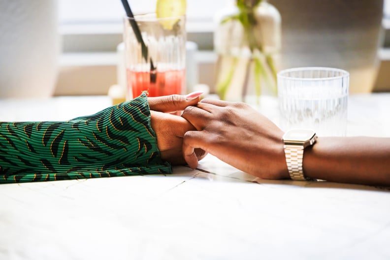 Two Individuals Holding Hands At the Dinner Table