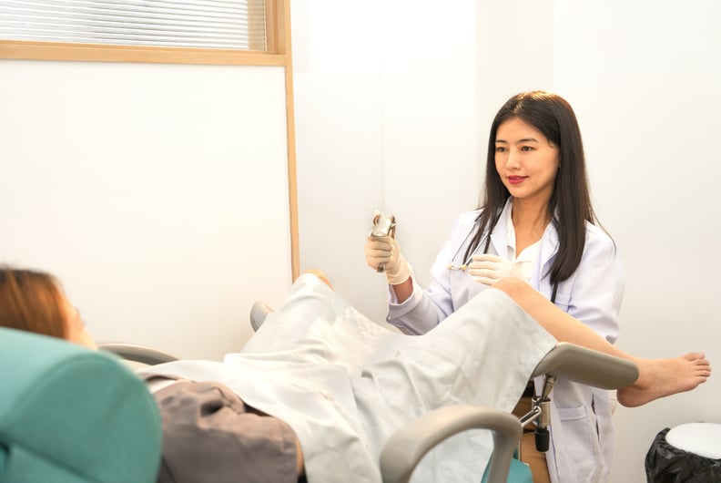 scene of a woman gynecologist is wearing medical gloves and doing internal examination of a female patient or pregnant woman that lying on a gynecological chair in the medical treatment room