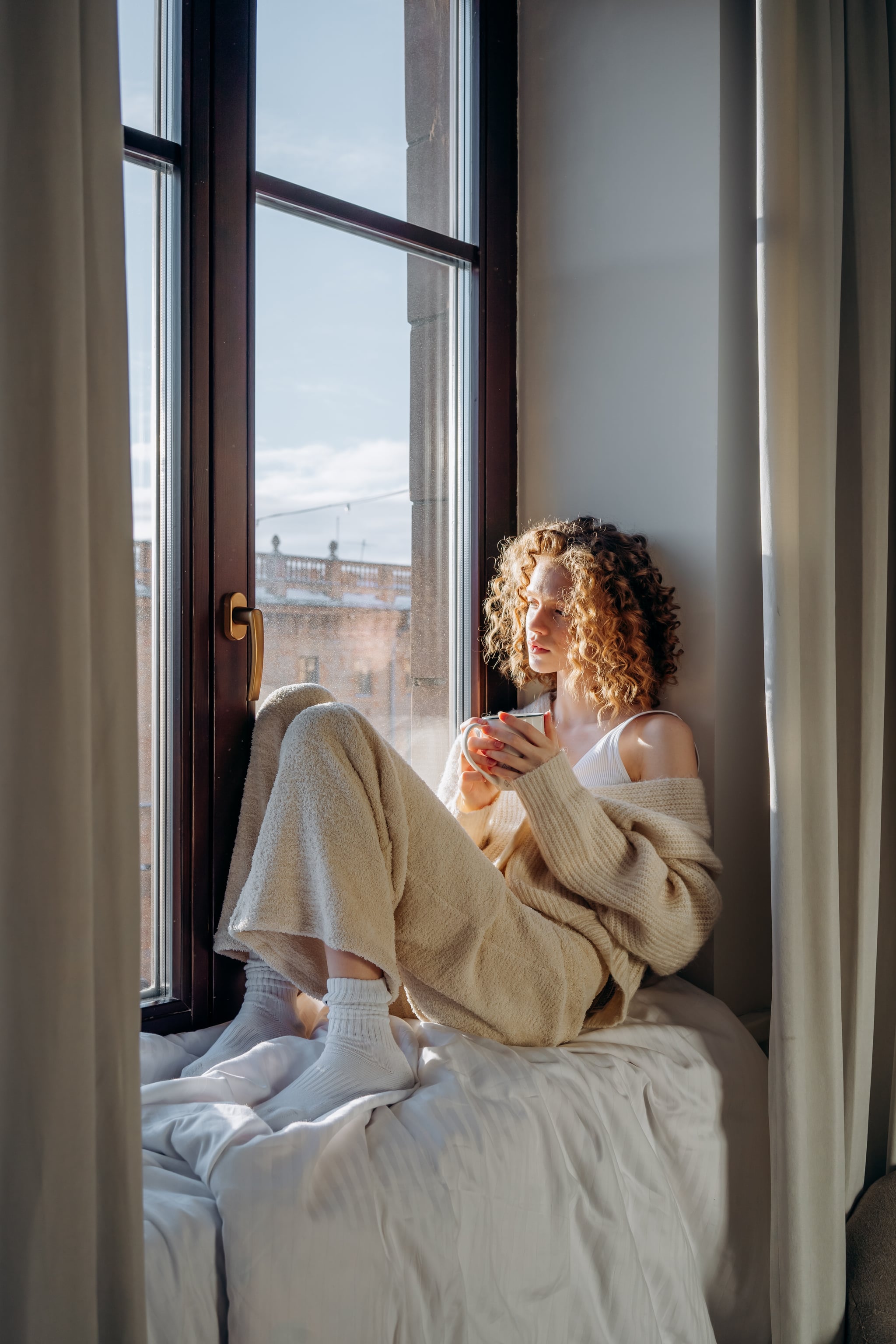 woman sitting in window during winter contemplating mercury retrograde december 2022-January 2023
