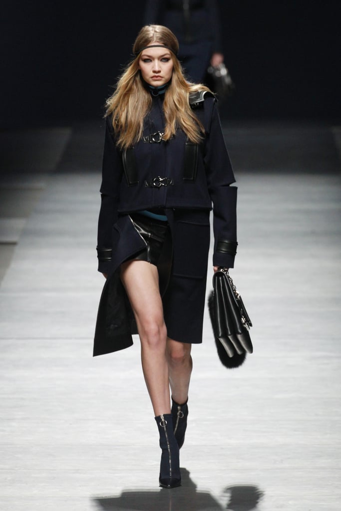 Gigi worked a structured navy and black coat with edgy cutouts and hardware. Her outfit was complete with a satchel, zippered booties, and a headwrap.