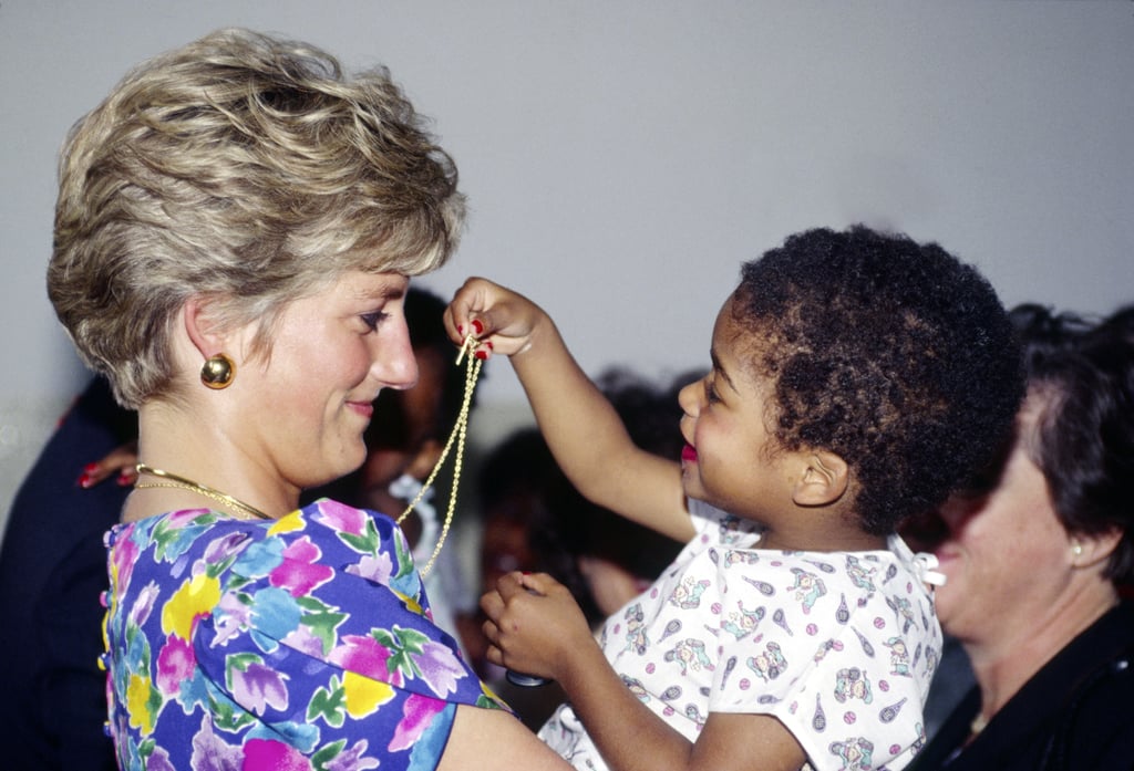 Diana let a little girl play with her necklace while visiting a hostel for abandoned children suffering from AIDS in San Paulo, Brazil, in April 1991.