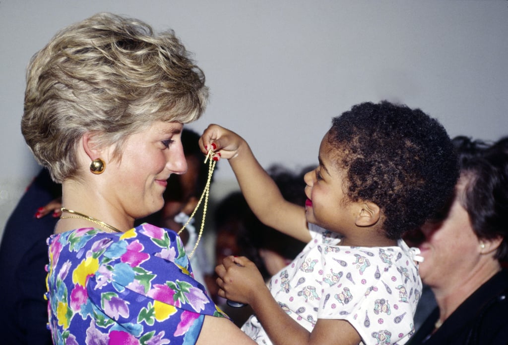 Diana let a little girl play with her necklace while visiting a hostel for abandoned children suffering from AIDS in São Paulo, Brazil, in April 1991.