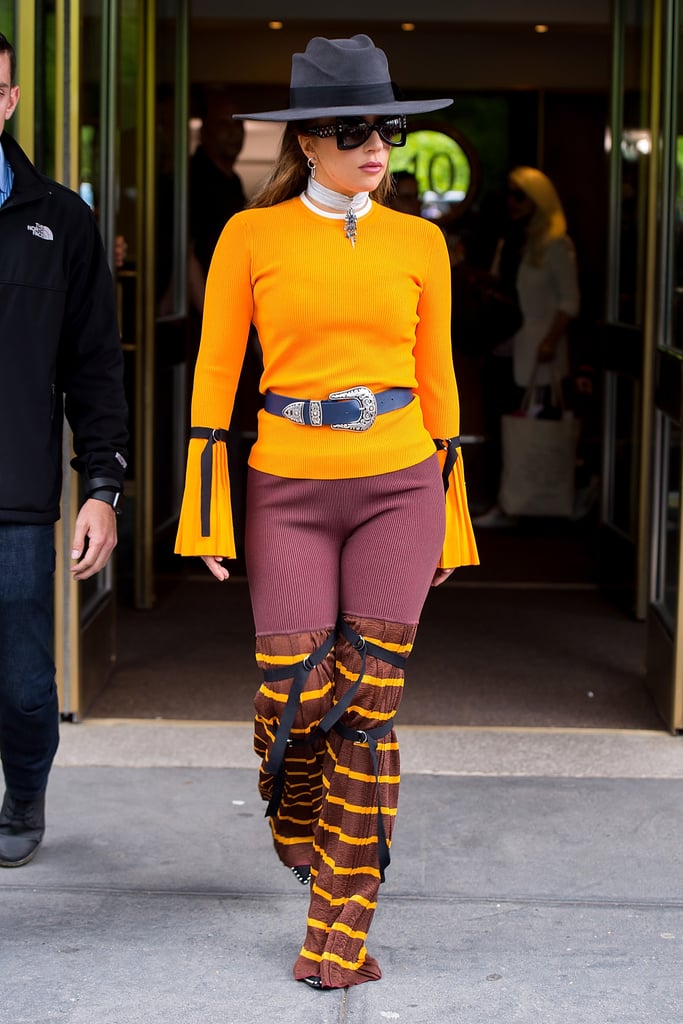 Wearing an orange knit with flared trousers and an Erickson Beamon choker.