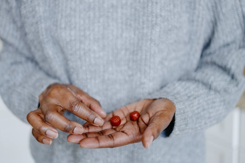 Close-up of unrecognizable black woman holding a pair of melatonin gummy supplements