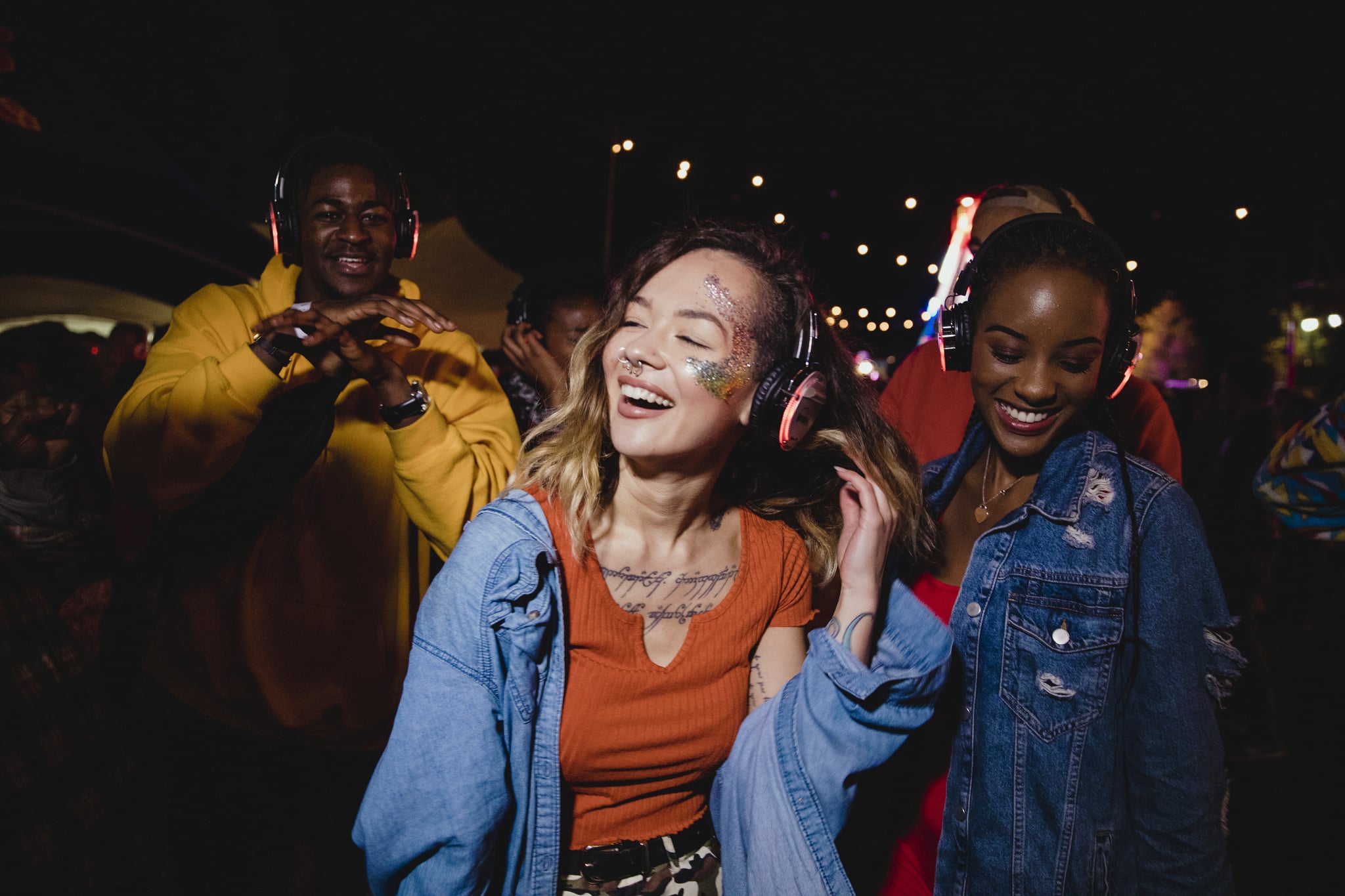Young woman is dancing in a silent disco with her friends.
