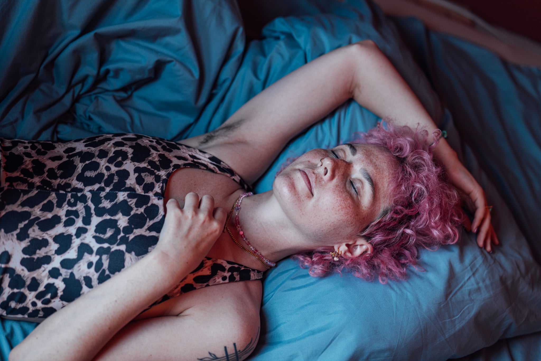 Woman Laying on Bed With Arm Resting on Top of Her Head