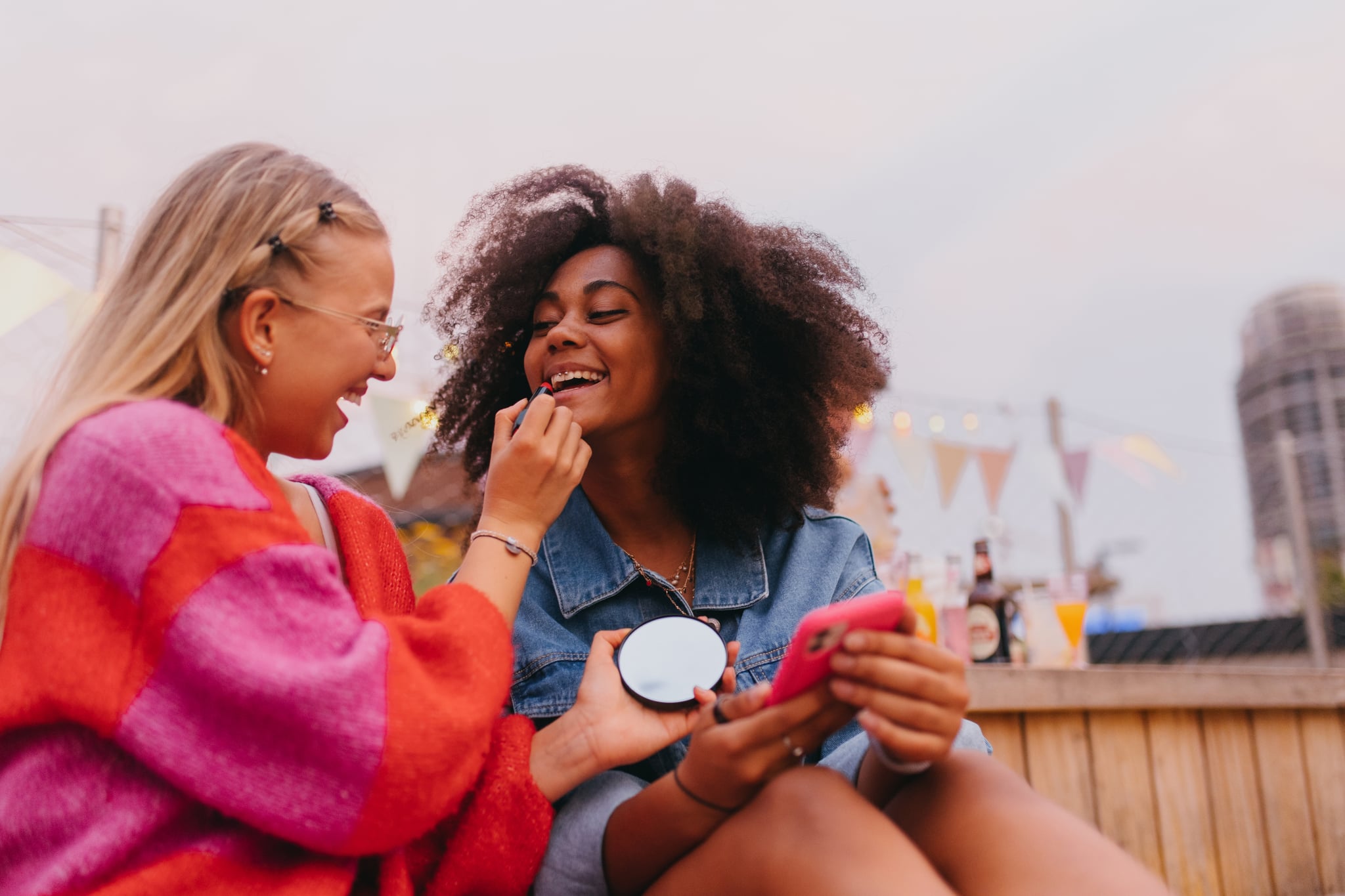 Two Friends Outside on Rooftop Putting Makeup on Each Other