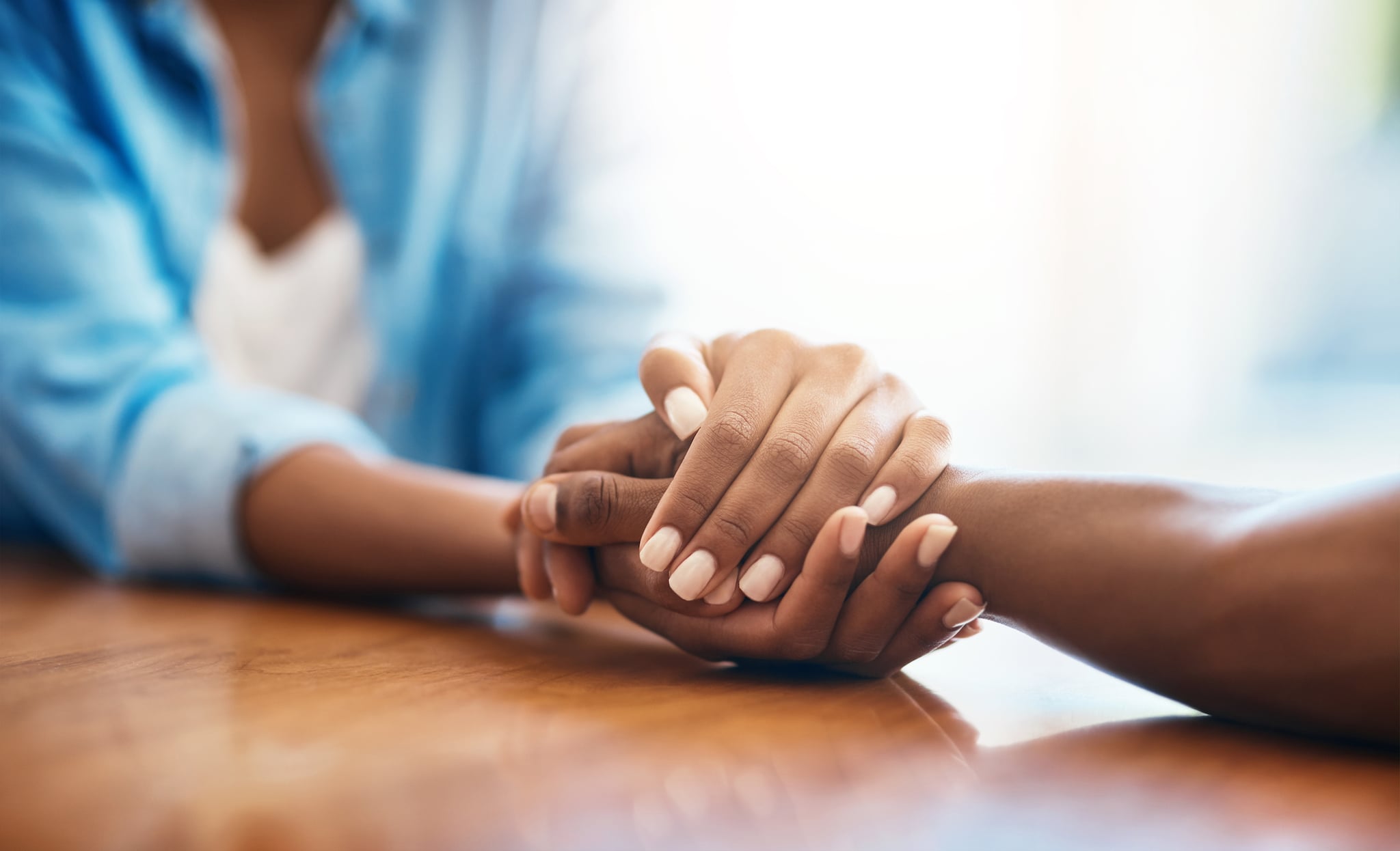 Closeup shot of two unrecognisable people holding hands in comfort at home