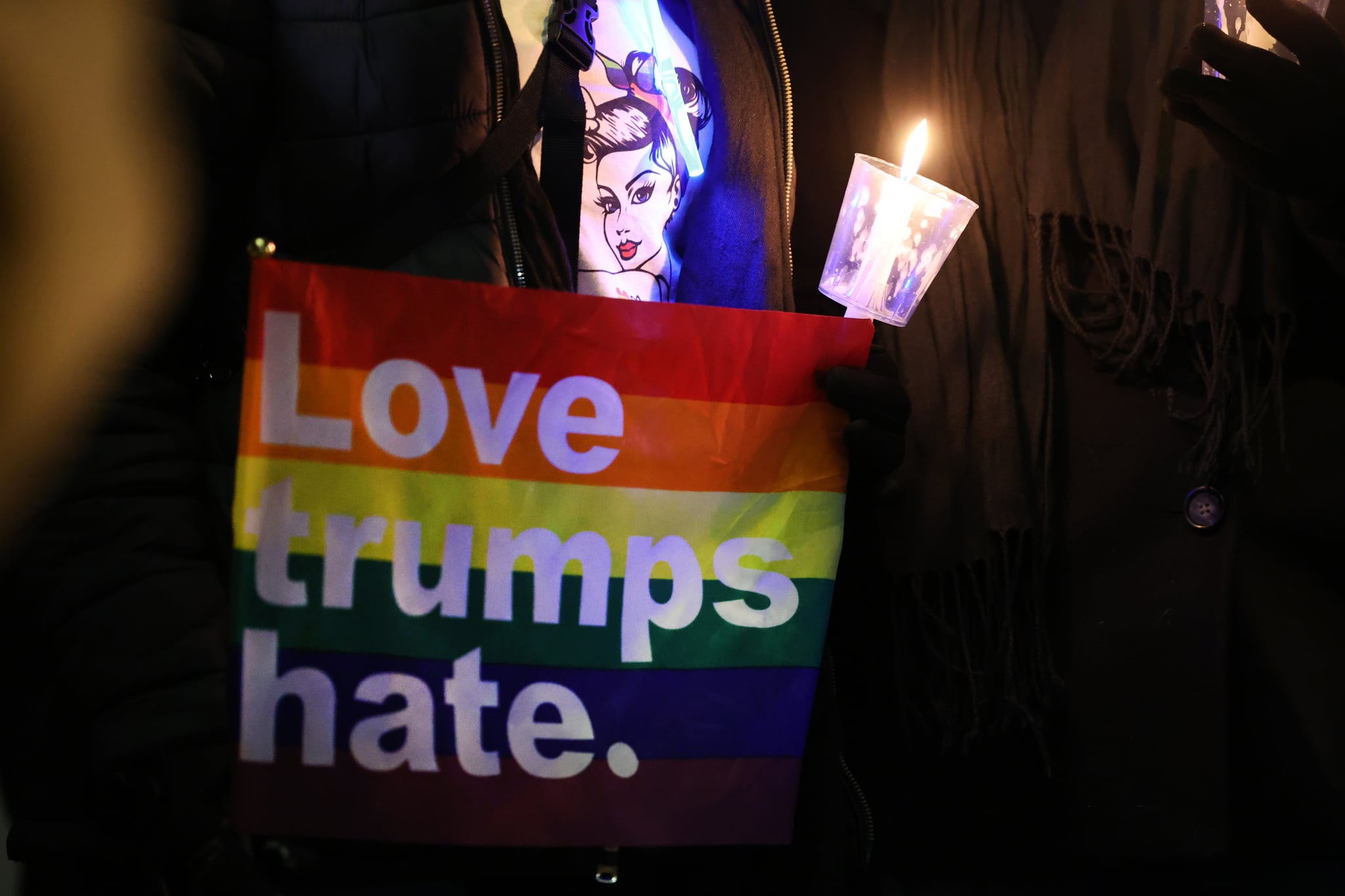 科罗拉多州科罗拉多斯普林斯- 11月21日:2022年11月21日，科罗拉多州科罗拉多斯普林斯，一名女子手持彩虹旗参观Q俱乐部夜总会附近的临时纪念馆。周六晚上，一名22岁的枪手进入LGBTQ夜总会并开枪，造成5人死亡，25人受伤，随后被俱乐部顾客制止。(斯科特·奥尔森/盖蒂图片社摄)