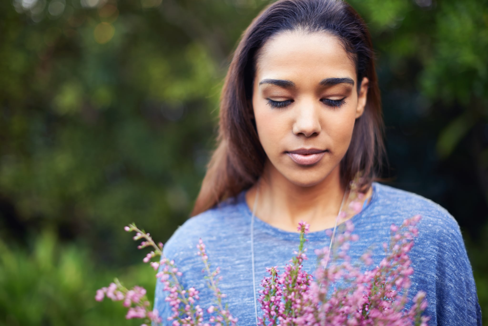 A young woman holding a bunch of flowers in a garden