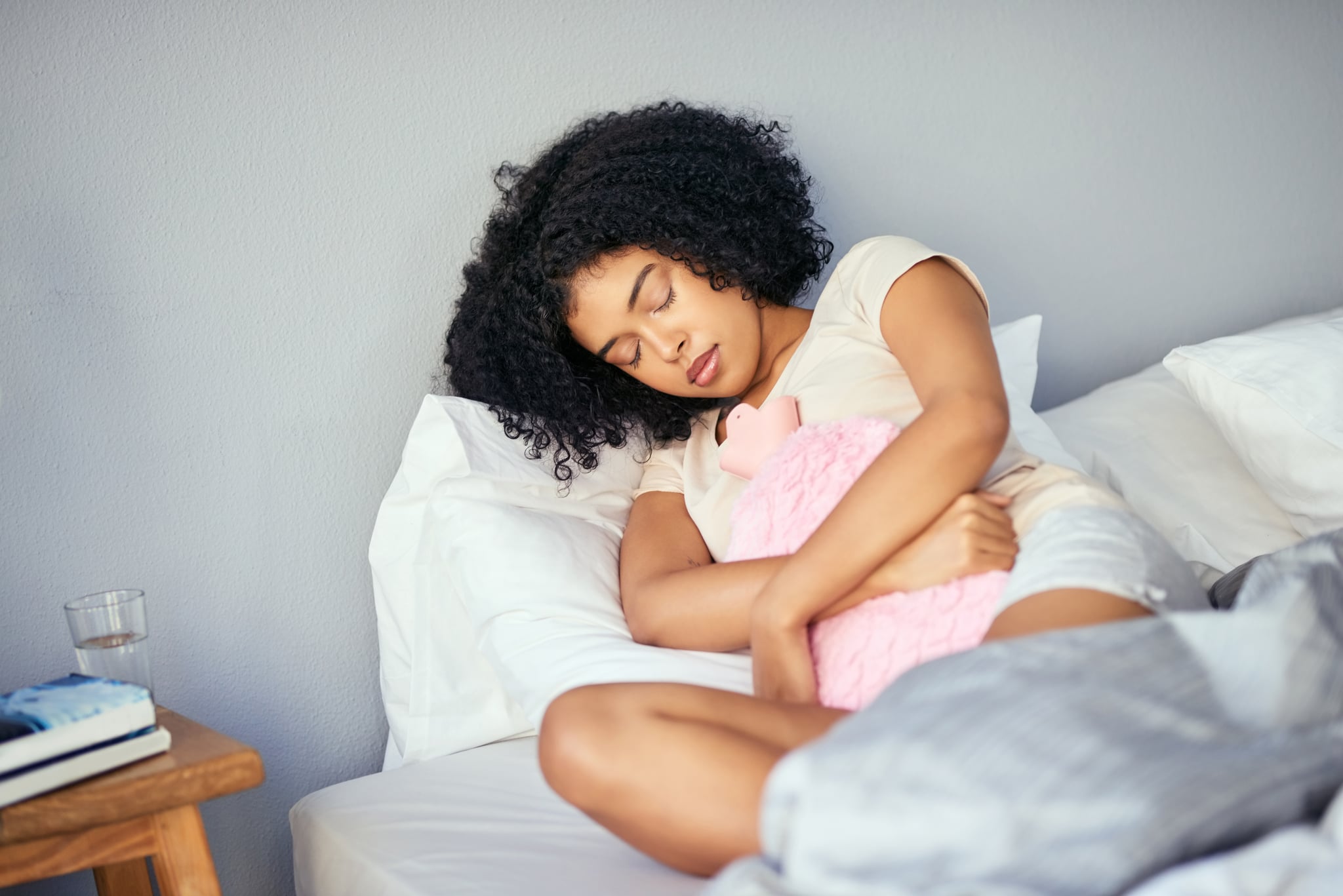 Shot of a young woman suffering from stomach cramps in her bedroom