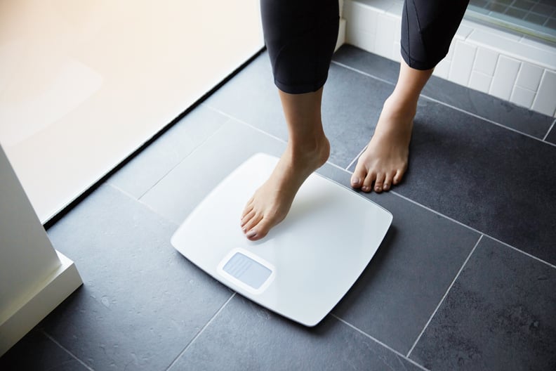 Woman steps on a scale for weight loss.
