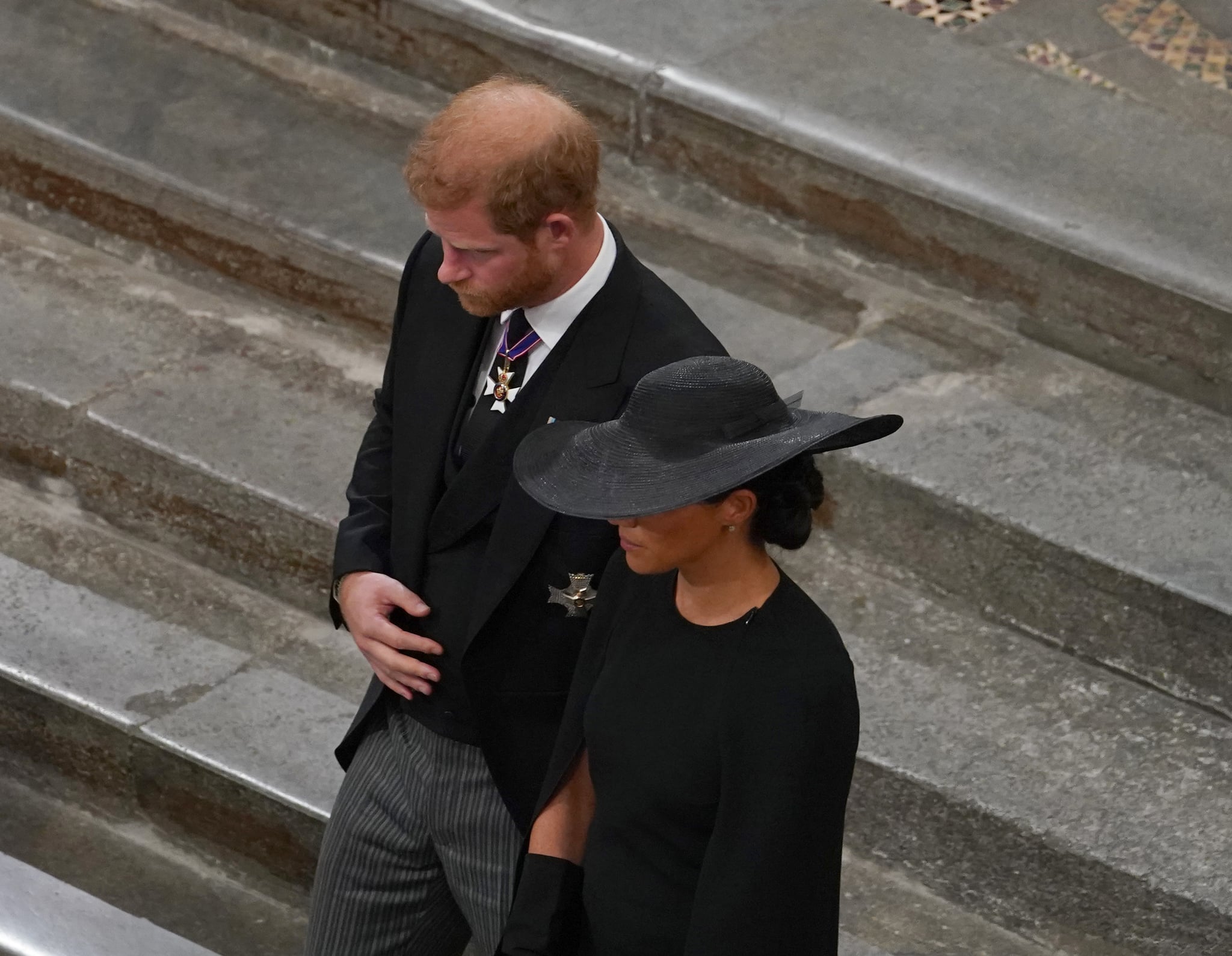 LONDON, ENGLAND - SEPTEMBER 19:  Prince Harry, Duke of Sussex and Meghan, Duchess of Sussex follow the bearer party with the coffin as they take part in the state funeral and burial of Queen Elizabeth II at Westminster Abbey on September 19, 2022 in London, England. Elizabeth Alexandra Mary Windsor was born in Bruton Street, Mayfair, London on 21 April 1926. She married Prince Philip in 1947 and ascended the throne of the United Kingdom and Commonwealth on 6 February 1952 after the death of her Father, King George VI. Queen Elizabeth II died at Balmoral Castle in Scotland on September 8, 2022, and is succeeded by her eldest son, King Charles III.  (Photo by Gareth Fuller- WPA Pool/Getty Images)