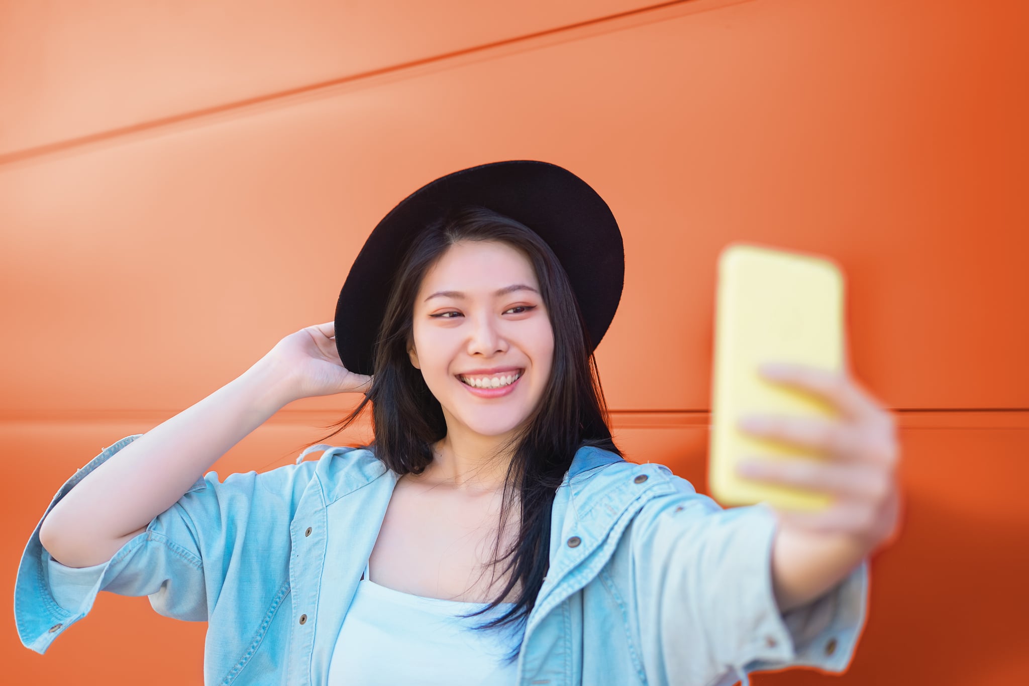 Happy Asian girl taking selfie with mobile smart phone outdoor - Trendy influencer having fun with new trends social networks apps - Millennial generation lifestyle people addicted technology
