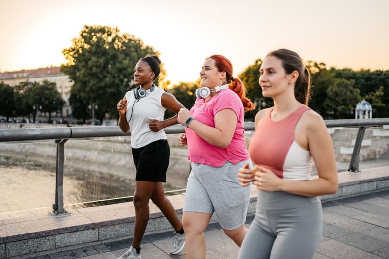 Three young female friends jogging on the bridge together, group cardio.