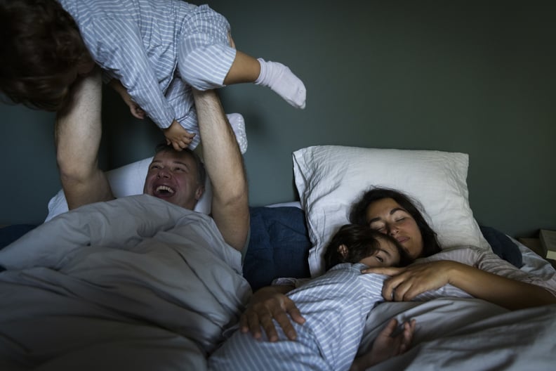 A photo shows a dad, mom, and two kids sleeping in the same bed.