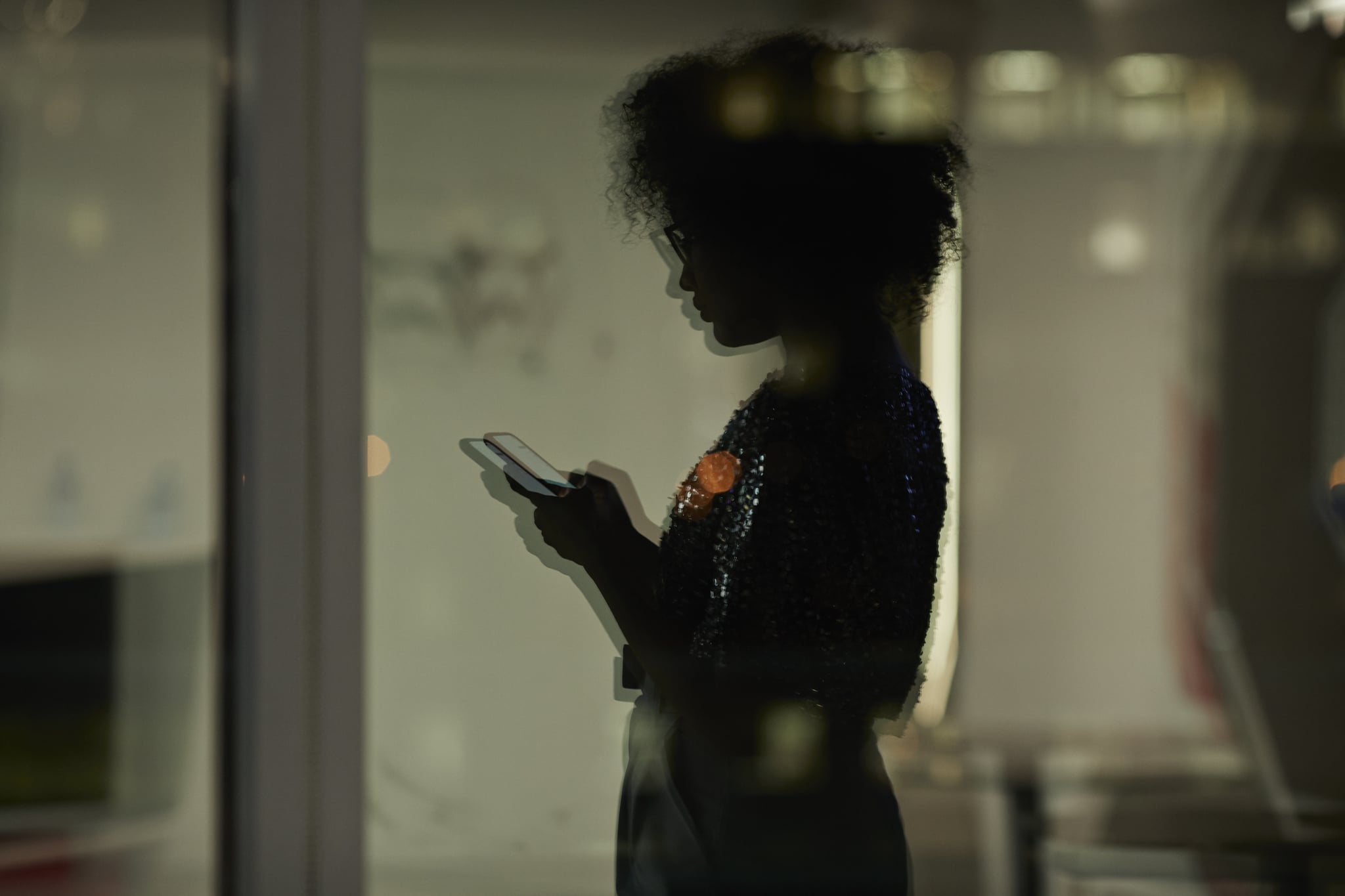 woman checking her phone in a dimly light office