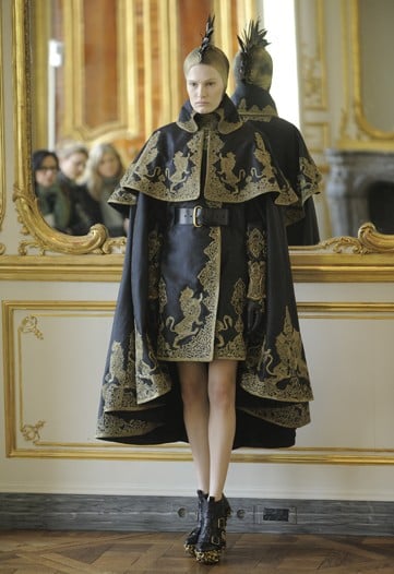 >> Yesterday, in a gilded salon at PPR's headquarters, Lee Alexander McQueen's final collection, consisting of 16 pieces, was presented. Each piece, topped with gold feather mohawk headpiece and finished off with hand-carved wooden-soled shoes, displayed digitally captured works of art — the angels of Sandro Botticelli and the demons of Hieronymus Bosch — woven into the fabric.  The solemn parade was set to the music McQueen had been listening to as he cut and fit the collection, sung by the German soprano, Simone Kerme.
Sarah Burton, McQueen's right hand and design assistant for 16 years, said that in the beginning of the Fall 2010 collection, McQueen had turned away from the world of the Internet, which he had harnessed for his last show. "He wanted to get back to the handcraft he loved, and the things that are being lost in the making of fashion. He was looking at the art of the Dark Ages, but finding light and beauty in it. He was coming in every day, draping and cutting pieces on the stand." At the time of McQueen's death, the 16 pieces shown had been 80 percent finished.
Tomorrow, retailers will be invited to buy a showroom collection spanning about 160 pieces.  The brand is expected continue with more commercial collections, and the clothes shown yesterday are not expected to be widely sold.  Instead, according to a spokewoman, they will be loaned out on a limited basis to a few fashion magazines.
Before his death, McQueen told LOVE: "I’m 40 now, but I want this to be a company that lives way beyond me, and I believe that customers are more important to making that happen than press. When I’m dead, hopefully this house will still be going. On a spaceship. Hopping up and down above the earth.”  For the moment, the design future of the label rests on the shoulders of the studio team led by Burton. “That will continue for the foreseeable future,” a spokesman said.