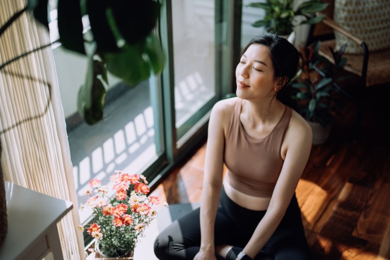 Woman practicing yoga for anxiety. Shown in a seated position, taking a deep breath with her eyes closed.