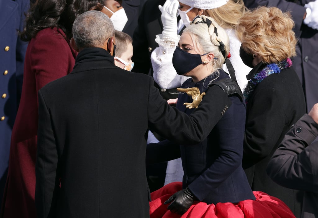 Barack Obama: "Also, can we discuss this dress of yours? And the braided hairstyle? Girl, you are giving me Effie Trinket from Hunger Games vibes, and I mean that in the most polite way possible. I'm here for it."
Lady Gaga: "Sheesh, you are on a roll with the compliments today, Barry! But thank you — I couldn't have done it without the folks at Schiaparelli. They custom-made the dress for the occasion, and I added the gold dove as a sign of peace, 'cause we could all use more of that after the past four years, wouldn't you agree?"
Barack Obama: "You have no idea how much I agree with ya on that."