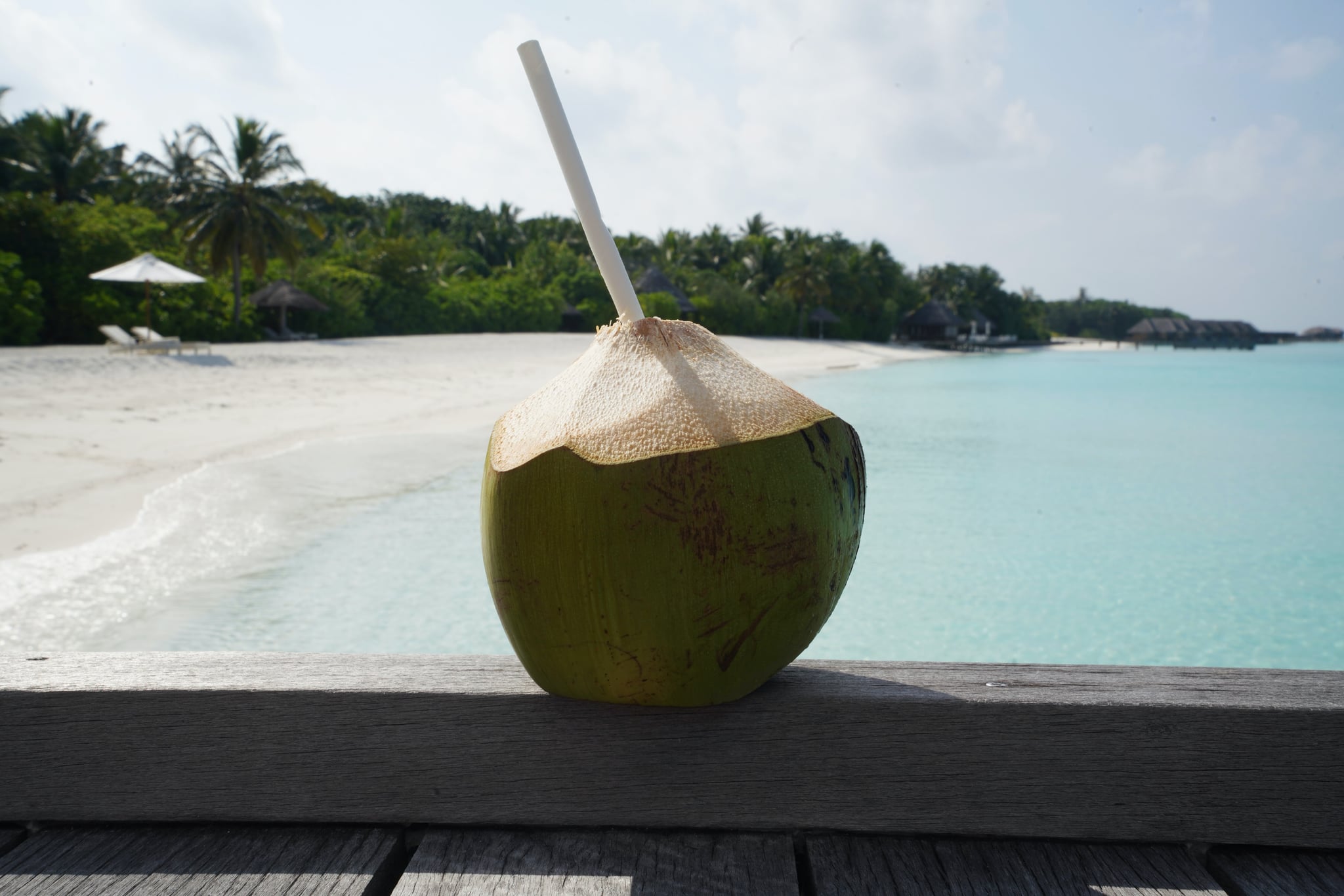 fresh coconut with a straw on a beach: is coconut water good for you?