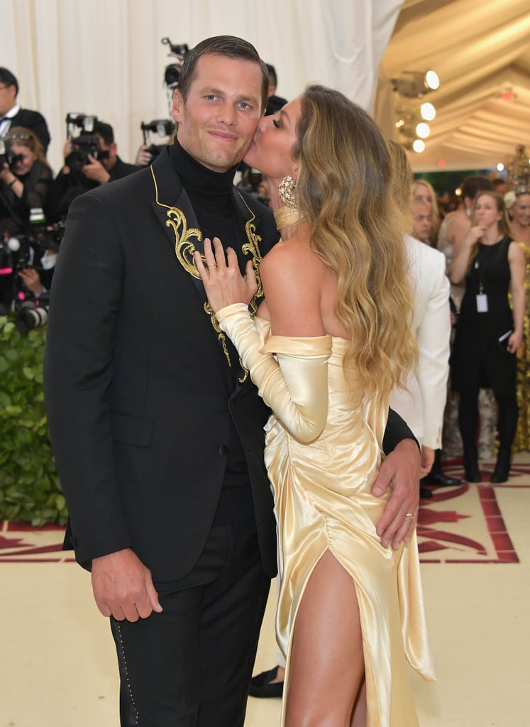 Celebrity couples are known for turning the Met Gala into their own personal date night, but none of them do it quite like Gisele Bündchen and Tom Brady — and this year was no different. On Monday, the couple steamed up the star-studded event, as per usual, when they arrived in matching Versace ensembles. Gisele let her hair down and wore a gold dress with a thigh-high slit and Tom donned a black suit with a turtleneck. The pair played up their PDA while posing for the cameras, and honestly, it should be a sin for them to look this good. Read on to see more of their sexy night out!