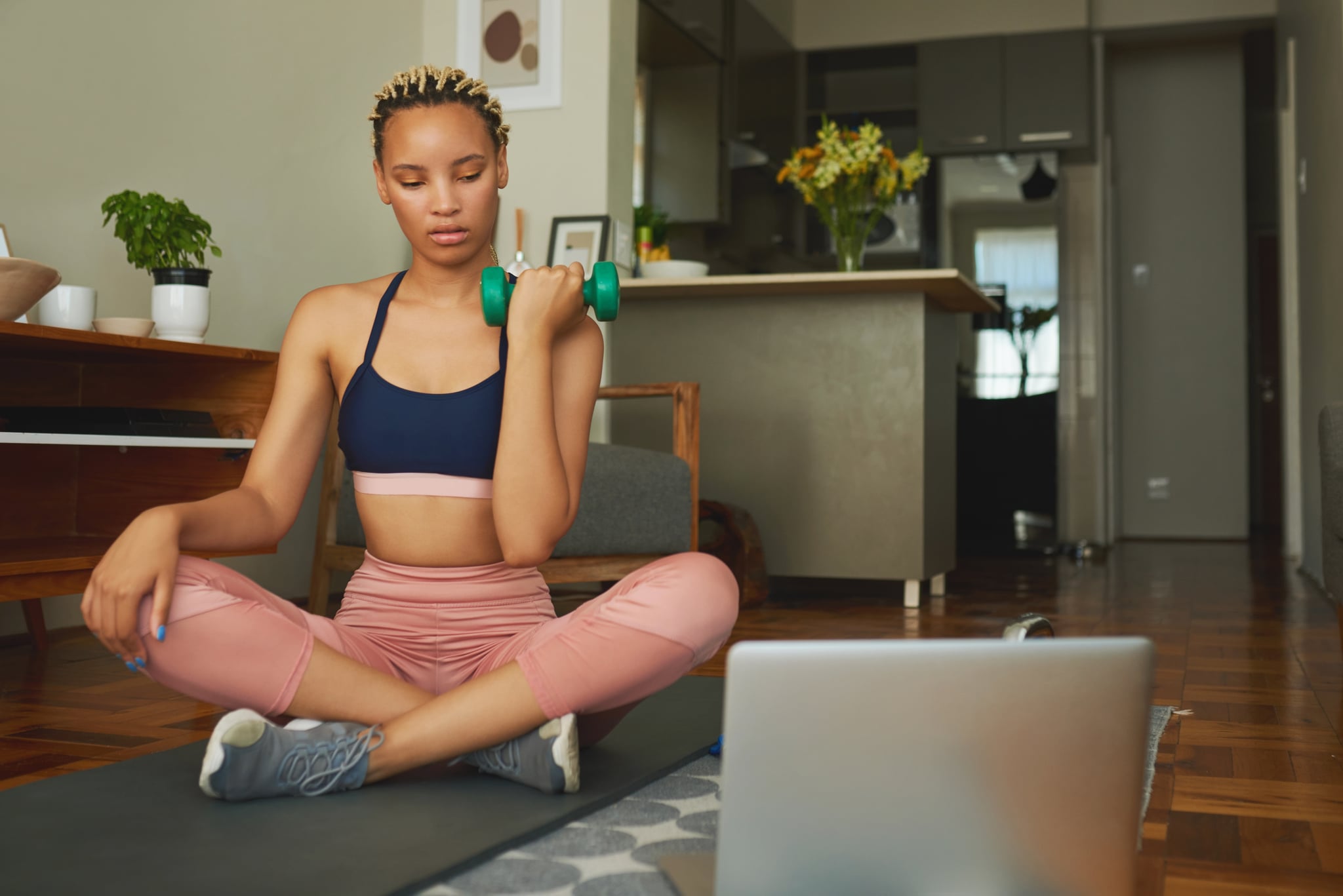 Woman working out at home, preventing strength-training injuries.