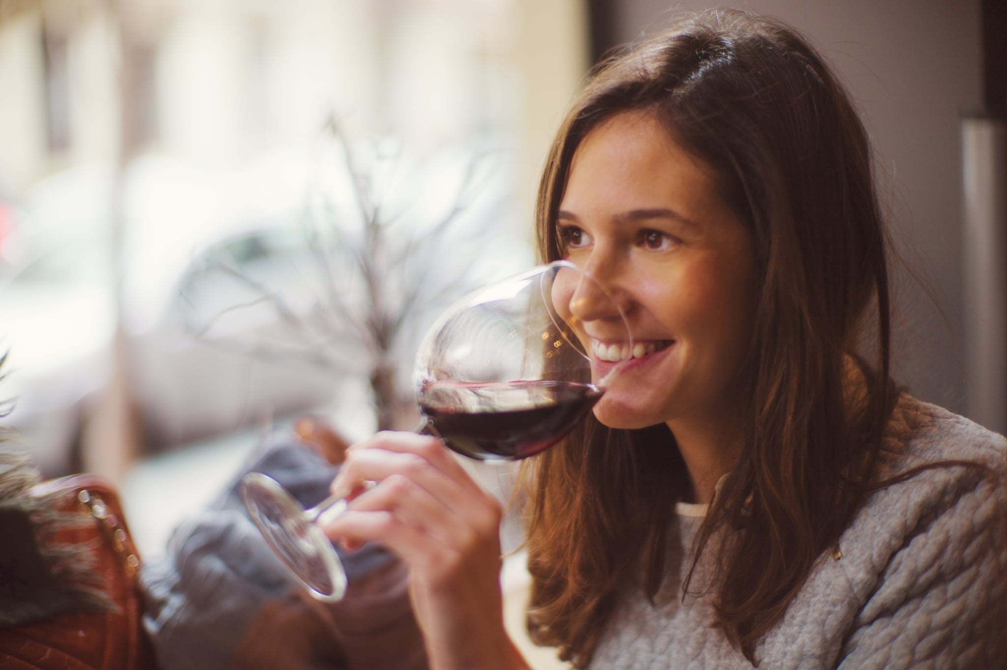 Beautiful happy lady drinking glass of red wine.