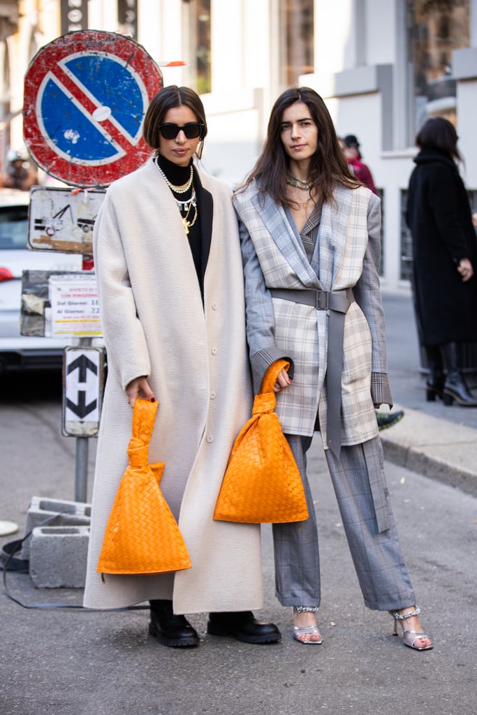 Above: Two showgoers carrying matching Bottega Veneta bags at Milan Fashion Week in February 2020.
Seleen Saleh, who's photographed street style around the world and just released her book, Street Culture, documenting the street style of BIPOC creatives, put her finger on it right after the images from Copenhagen Fashion Week first hit, telling us, "The images coming out of Copenhagen were refreshing! There was more focus on Black showgoers and great style. There was also less focus on influencers."
The sentiment when we spoke with both Seleen and Acielle, of Style du Monde — who captures images for Vogue, The New York Times, and POPSUGAR — is that street style will reflect the larger reprioritization the whole industry is making. "I'm mostly looking forward to more inclusivity and diversity in the fashion world. Sustainability is more than a trend. We see fashion brands practicing zero waste and slow fashion, upcycling and recycling," Acielle told us of the things that are getting her excited for the future. And if we connect the dots, that emphasis on slowing down and thinking about sustainability and about representation (which has been so seriously lacking from the industry) means we're reimagining who and what we want to see from street style, too. That could mean less from big brands, fewer It items, and more from micro influencers, who are engaging with smaller labels, showing off vintage and recycled clothing. And like Seleen suggests, Copenhagen's street style is our early indication that that's already happening.