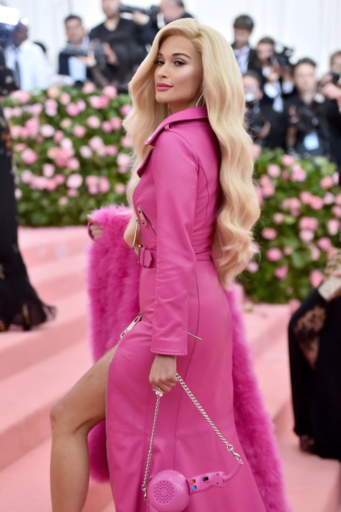 Come on, Barbie, let's go party! Kacey Musgraves made her first-ever Met Gala appearance on May 6, and she must've gotten a memo about this year's pink carpet in advance of the star-studded event, because she matched it perfectly in an all-pink outfit by Moschino. To fit with the playful camp theme, the country singer wore a Barbie-inspired motorcycle dress with a matching feather boa, sunglasses, and blow-dryer handbag. The brunette even switched up her hair for the look, sporting a big blond wig. 
Kacey teased her look prior to hitting the red carpet by sharing various photos of teeny doll accessories. It was only right, then, that she also pulled up in a pink convertible. See photos of her hyperbolically feminine look ahead.

    Related:

            
            
                                    
                            

            These Met Gala Looks Are Dramatic Enough to Entertain You For the Rest of the Year