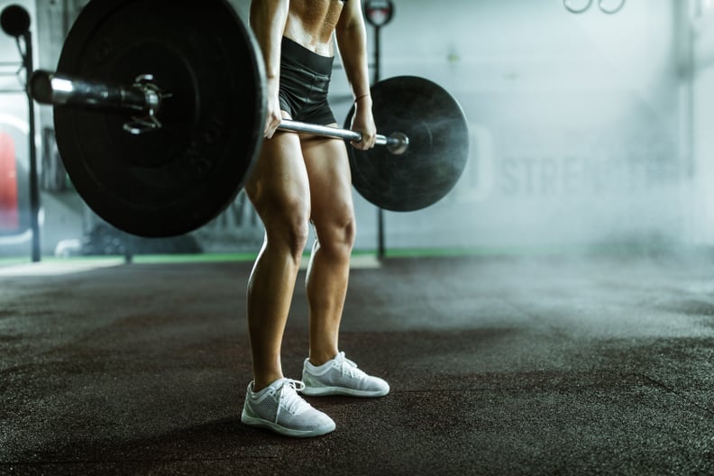 Athletic woman lifting barbell in a gym.