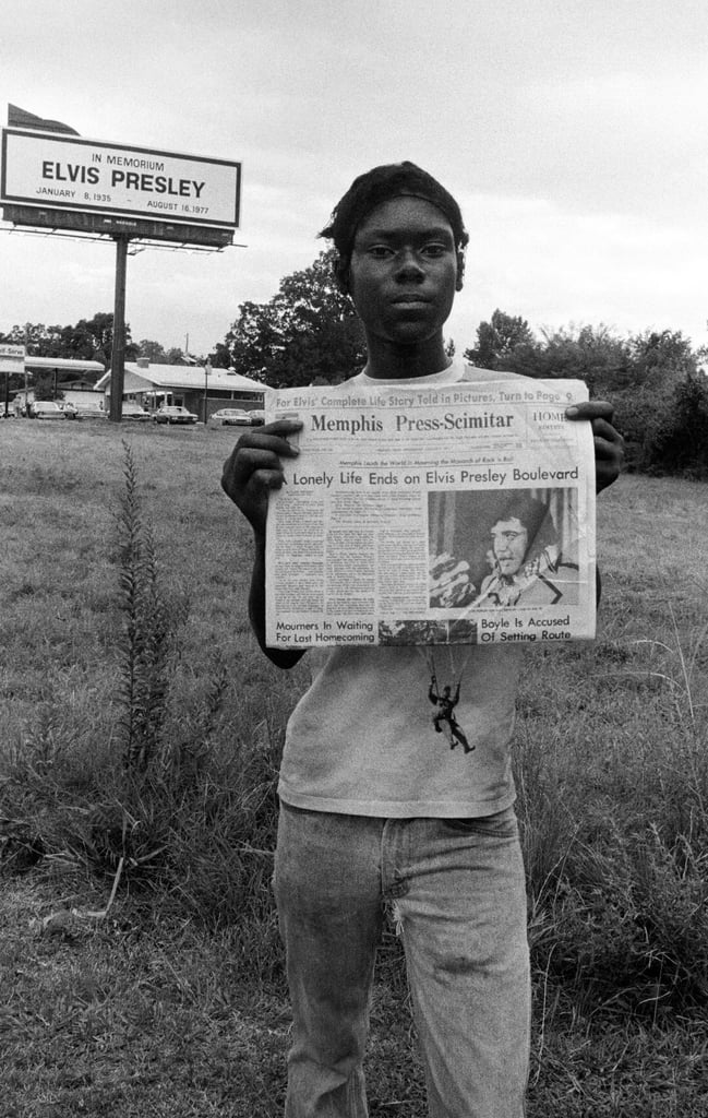 A mourner holds up a newspaper with the headline, "Lonely Life Ends on Elvis Presley Boulevard."