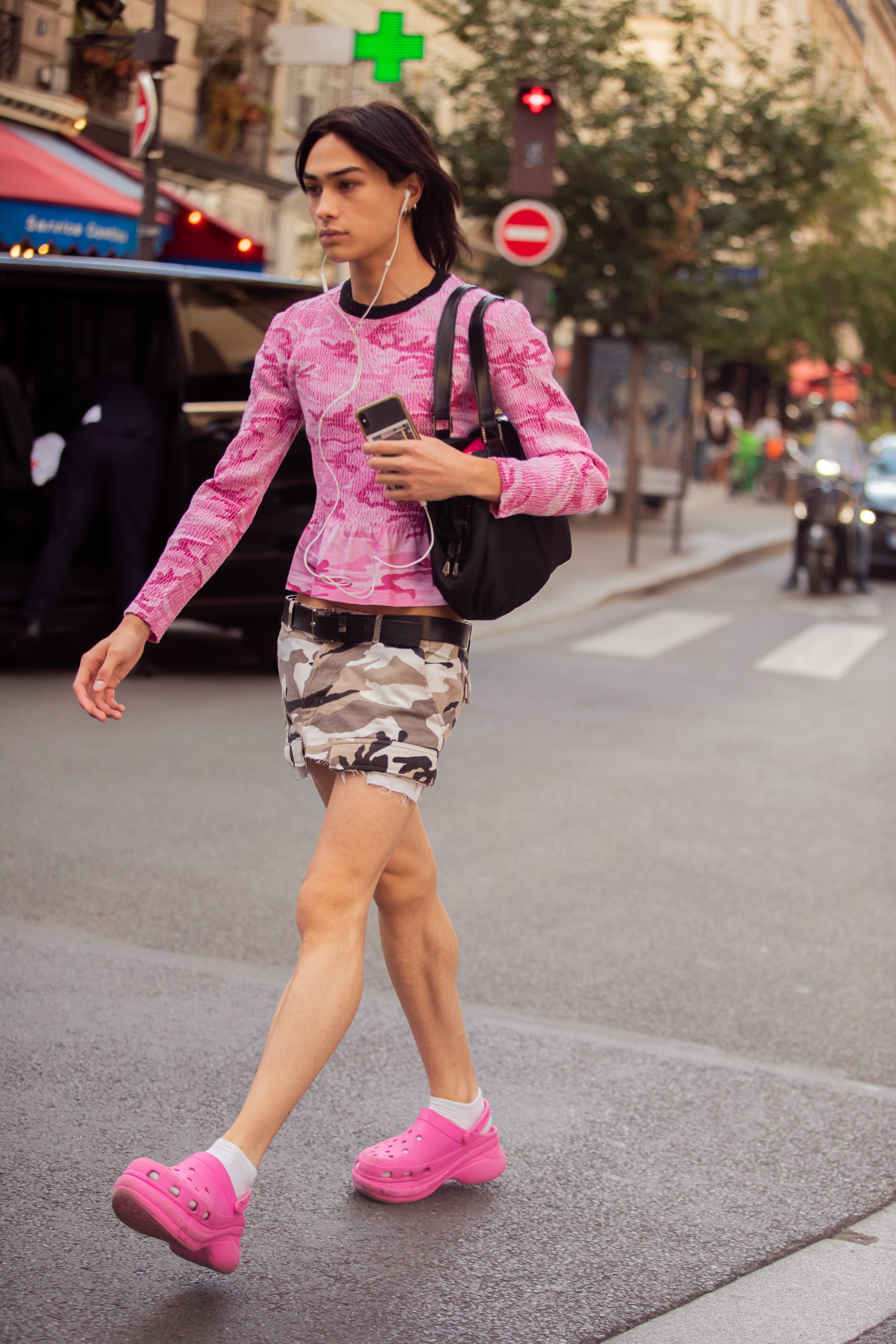 PARIS, FRANCE - JUNE 24: A guest wears a pink longsleeve peplum knit camouflage top, low-rise gray camouflage caro mini skirt with a black belt, hot pink Crocs, and white socks during Paris Fashion Week Mens Spring/Summer 2023 on June 24, 2022 in Paris, France. (Photo by Melodie Jeng/Getty Images)