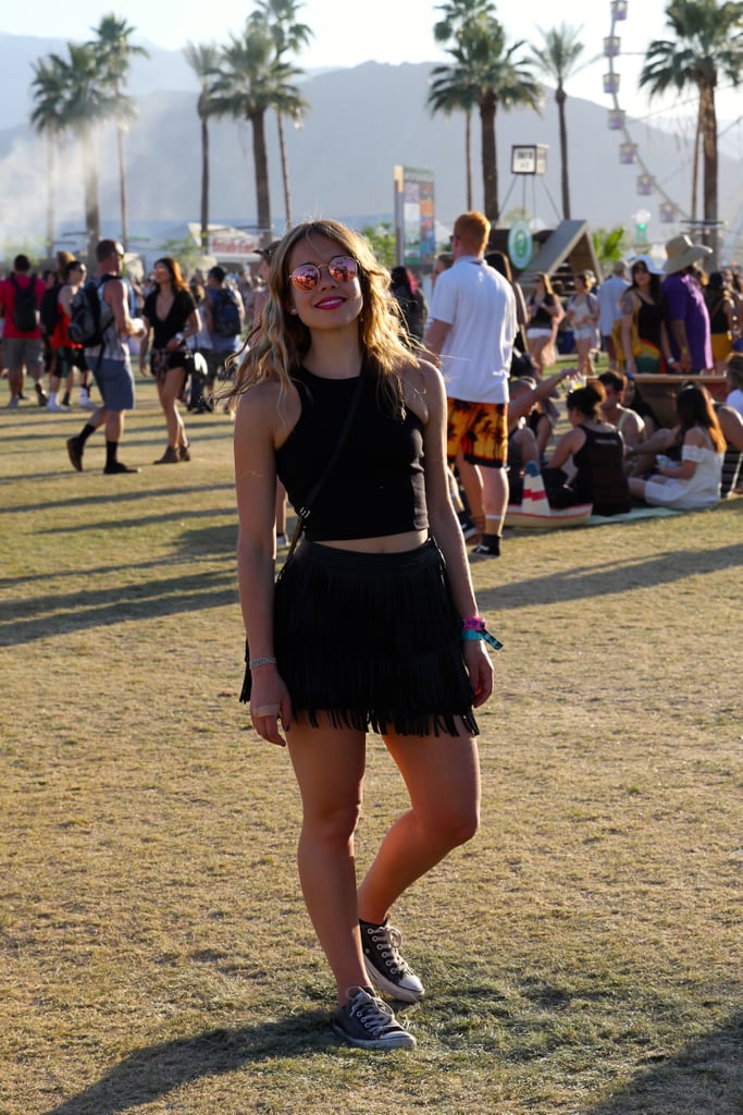Sarah Wasilak, Editorial Assistant at Popsugar Fashion, wore a fringe H&M miniskirt, completing her look with a black Y-neck Tobi crop top, leather Converse sneakers, and mirrored Ray-Ban sunglasses.