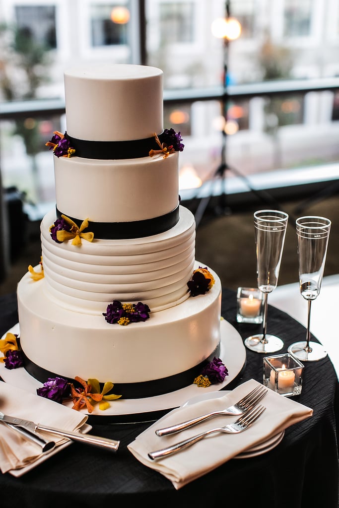 Black ribbon and a few bright flowers pop against the white frosting on this modern stunner.