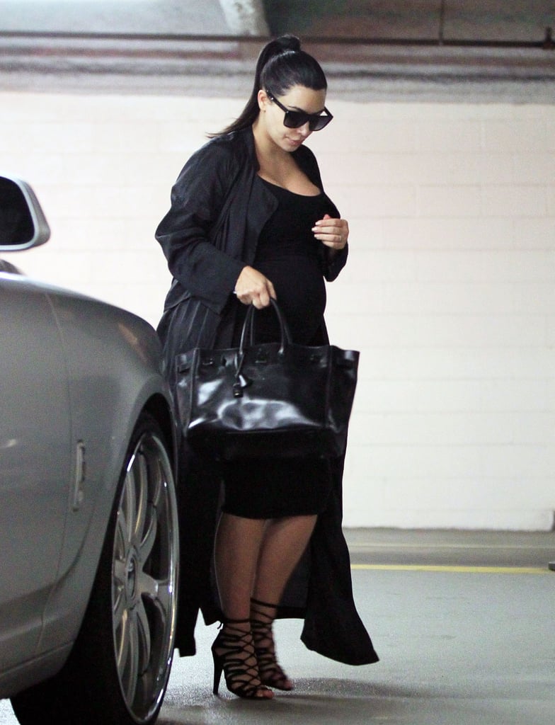 Kim stuck to her black basics: a body-con knee-length dress, strappy sandals, a longline duster coat, and her trusty satchel.