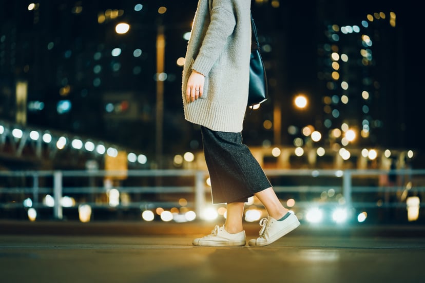 Cropped image of woman walking in the illuminated urban city at night