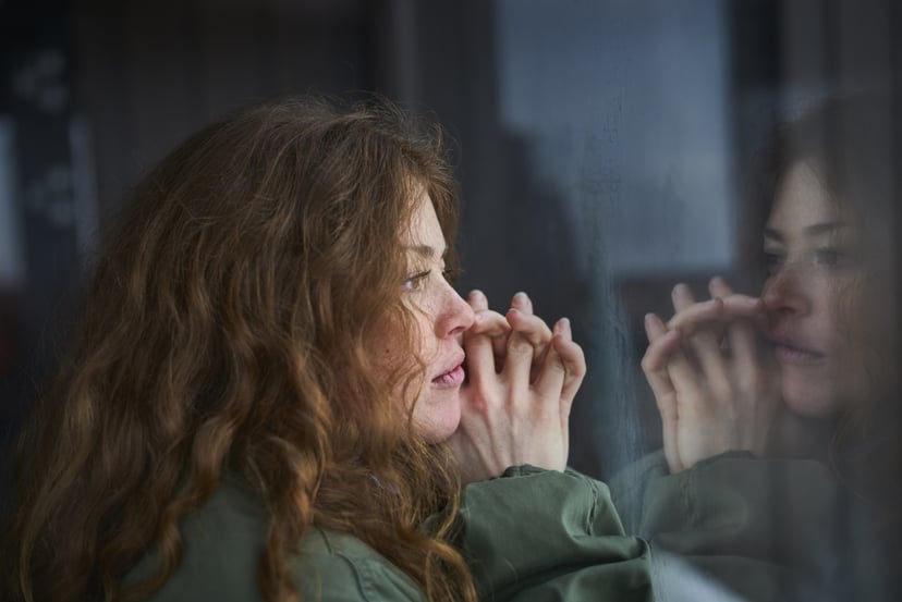 woman looking out window thinking about mental health.