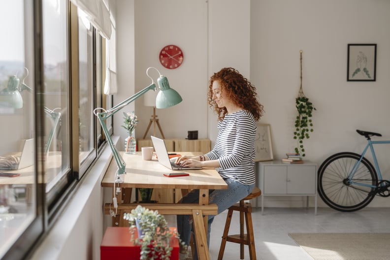 Woman sitting on a desk using a laptop computer while changing desktop folder icons.