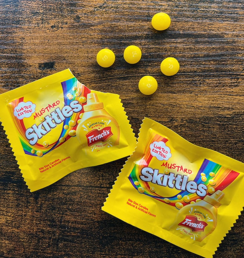 Two packages of French's mustard-flavored Skittles candies.